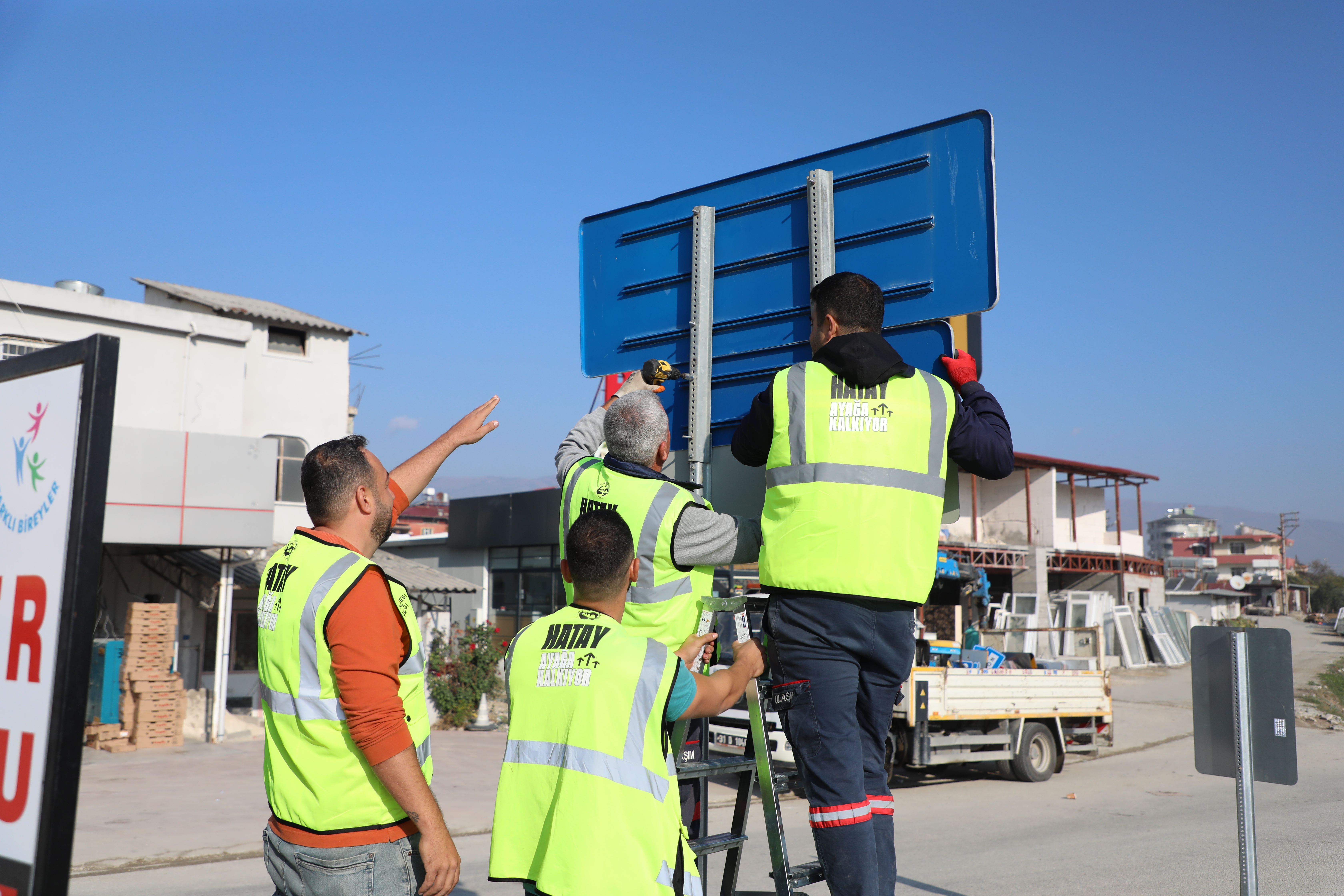 Hatay Büyükşehir Belediyesi, deprem sonrası şehirdeki adres belirsizliklerini gidermek ve güvenli ulaşımı sağlamak için fosforlu levhalar yerleştiriyor. Yeni levhalar gece görünürlüğü artırıyor.